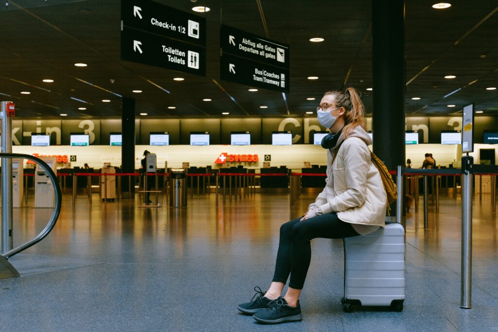 Passageira a espera sobre a mala no saguão do aeroporto